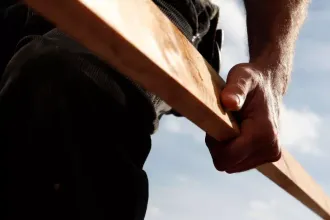 Dachhandwerker mit Holzbalken in der Hand